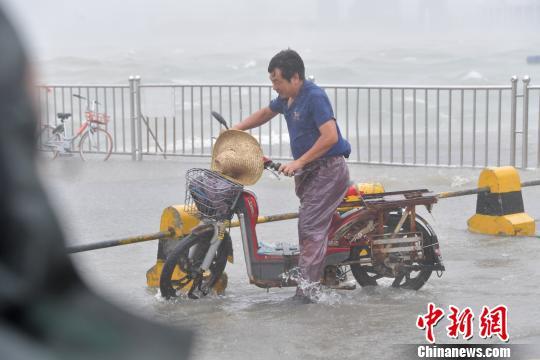 深圳市平易近雨水中艰巨前行。　陈文 摄